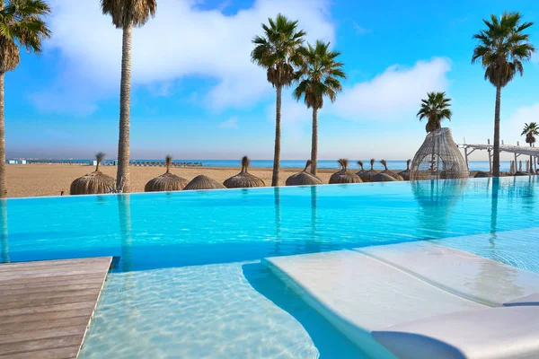 Resort piscina a sfioro in una spiaggia con palme — Foto Stock
