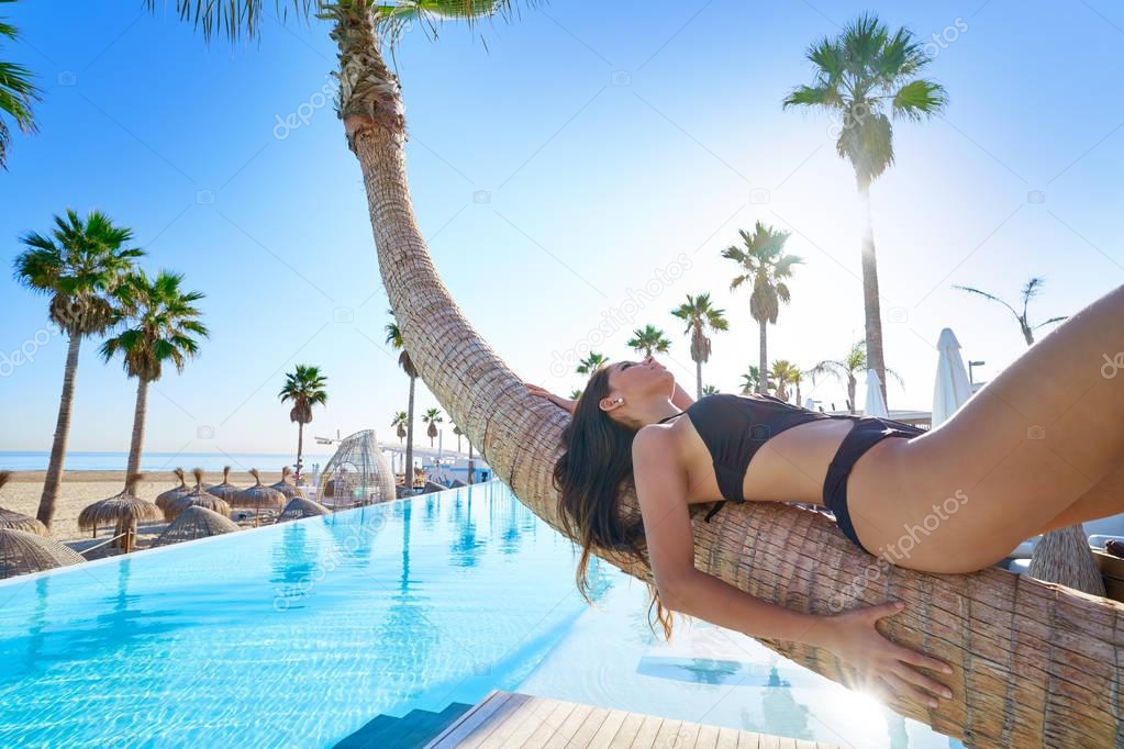 woman lying on pool bent palm tree trunk
