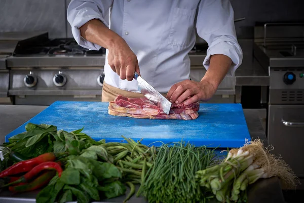 Руки шеф-повара режут мясо на кухне ресторана — стоковое фото
