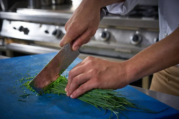 Kuchaři ruce řezání pažitka v kuchyni restaurace — Stock fotografie