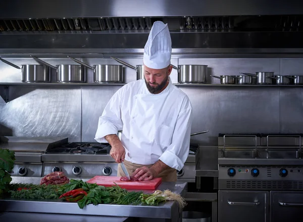 Шеф-повар режет мясо на кухне ресторана — стоковое фото