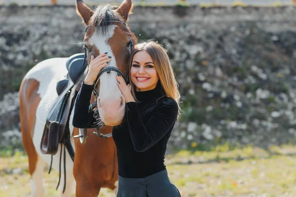 若い女性理学療法士は茶色の馬を世話しています 顎の溝で治療を行う女性 — ストック写真