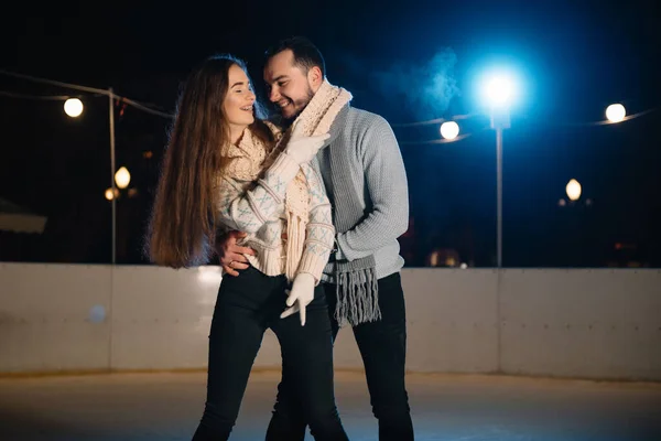 男人和女人年轻的家庭快乐的微笑牵着手滑板在冬夜的溜冰场上 带着爆竹灯 — 图库照片