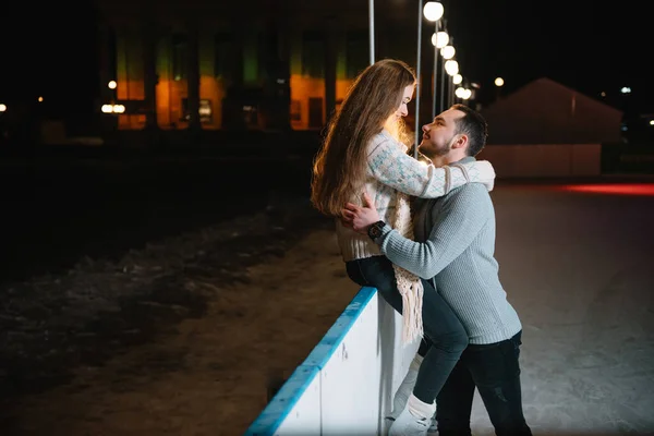 恋爱中的年轻夫妇 在冰场约会 一个女孩坐在护栏上和她的男朋友接吻 — 图库照片