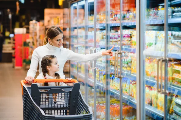 Güzel bir anne elinde market sepeti, elinde çocuğuyla süpermarkette yürüyor. Sağlıklı alışveriş..