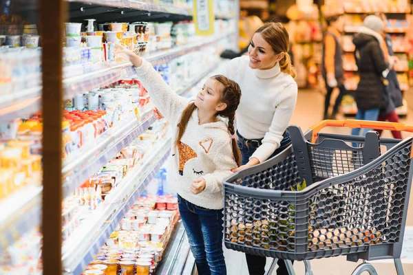 Güzel bir anne elinde market sepeti, elinde çocuğuyla süpermarkette yürüyor. Sağlıklı alışveriş..