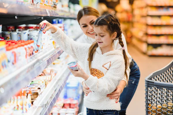 beautiful mother holding grocery basket with her child walking in supermarket. Shopping for healthy.