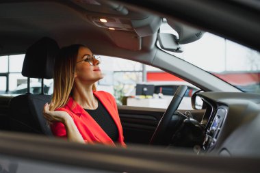 Bir arabanın dikiz aynasına bakan genç bir kadın.