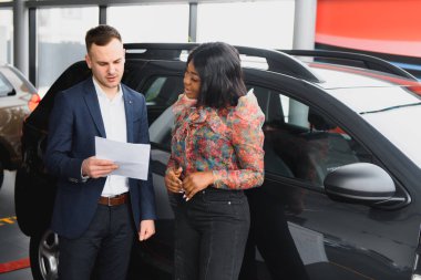 Güzel, genç bir Afrikalı kadın galeriden araba alıyor.