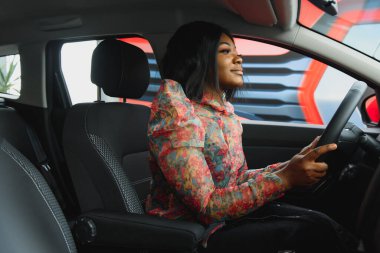 Arabayı kadınlar alıyor. Araba galerisindeki kadınlar. Siyah kızlar kırmızı arabanın yanında.