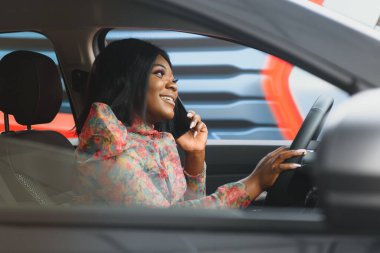 Mutlu bir Afrikalı kadın yeni bir araba kullanıyor.