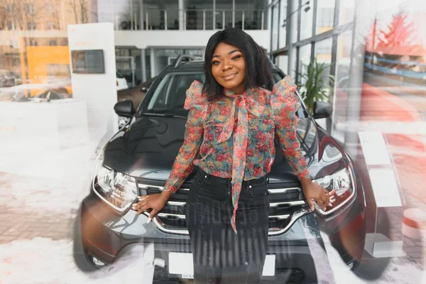 Woman buying the car. Lady in a car salon. Elegant black girl