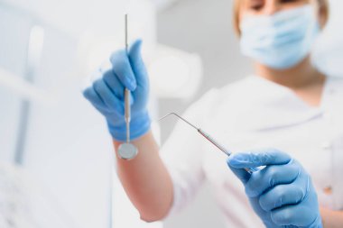 Klinikte elinde diş aletleri tutan bir dişçinin portresi.