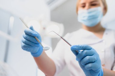 Klinikte elinde diş aletleri tutan bir dişçinin portresi.