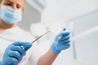 Klinikte elinde diş aletleri tutan bir dişçinin portresi.