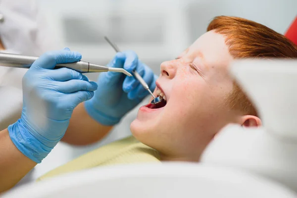 Dentist wearing mask. Red-haired child dentist wearing mask examining cute boy