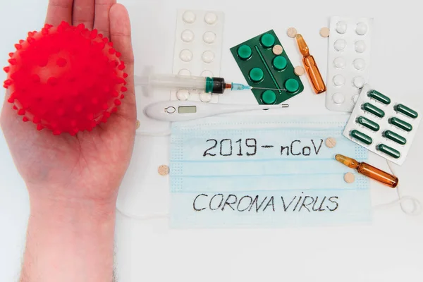 a test tube with a positive test for the CAVID-2019 coronavirus. medical devices on a white table. thermometer, phonendoscope, tablets, surgical masks