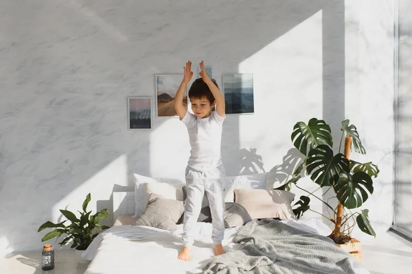 stock image Happy kid in pajama jumping on the bed and having fun in the morning.