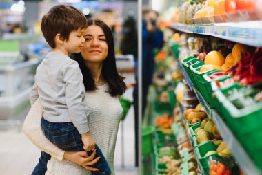 Genç anne ve küçük oğlu süpermarkette. Sağlıklı yeme kavramı