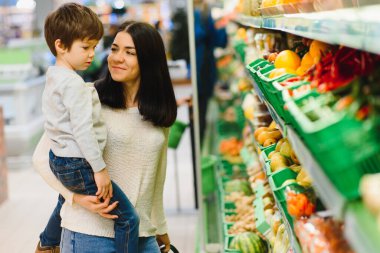 Genç anne ve küçük oğlu süpermarkette. Sağlıklı yeme kavramı