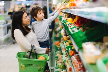 Genç anne ve küçük oğlu süpermarkette. Sağlıklı yeme kavramı