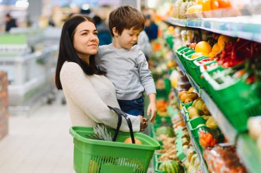 Genç anne ve küçük oğlu süpermarkette. Sağlıklı yeme kavramı