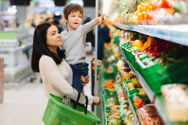 Genç anne ve küçük oğlu süpermarkette. Sağlıklı yeme kavramı