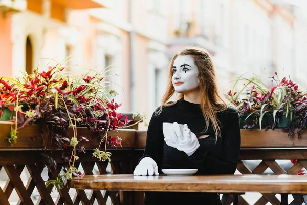 girl mime drinks coffee in paris. Mime comedian drinking coffee.