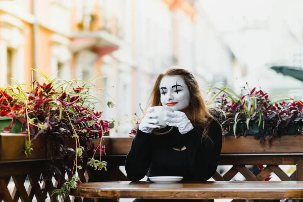 girl mime drinks coffee in paris. Mime comedian drinking coffee.