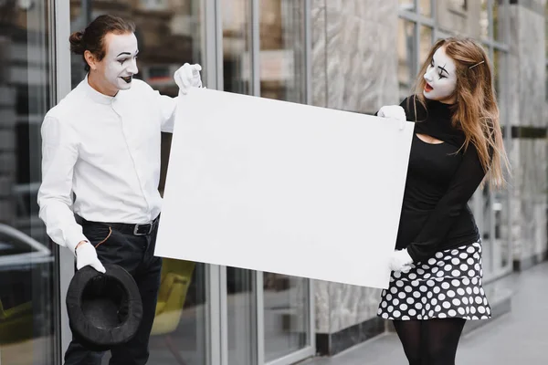 Your text here. Actors mimes holding empty white letter. Colorful portrait with gray background. April fools day