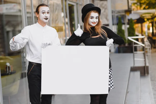 Your text here. Actors mimes holding empty white letter. Colorful portrait with gray background. April fools day
