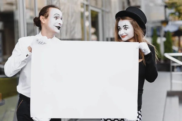 Your text here. Actors mimes holding empty white letter. Colorful portrait with gray background. April fools day