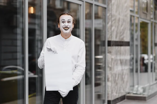 Your text here. Actor mime holding empty white letter. Colorful portrait with gray background. April fools day