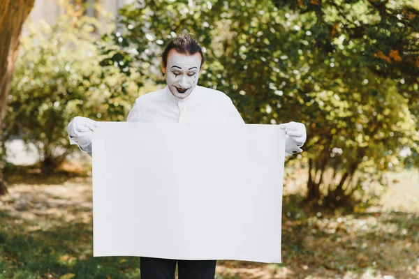 Your text here. Actors mimes holding empty white letter. Colorful portrait with green background. April fools day