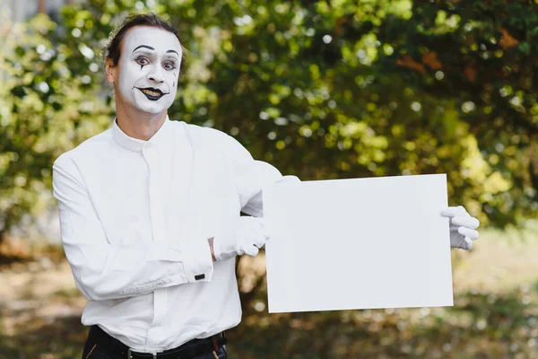 Your text here. Actors mimes holding empty white letter. Colorful portrait with green background. April fools day
