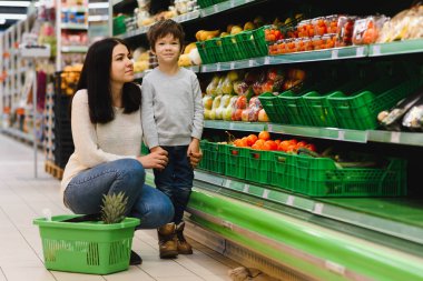 Genç anne ve küçük oğlu süpermarkette. Sağlıklı yeme kavramı