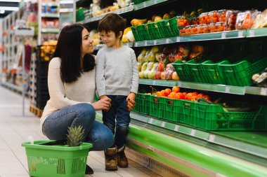 Genç anne ve küçük oğlu süpermarkette. Sağlıklı yeme kavramı