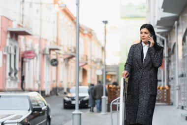 Şehirdeki çekici genç kadın. İş kadını, modern iş merkezinin önünde akıllı bir telefonla konuşurken gülümsüyor.