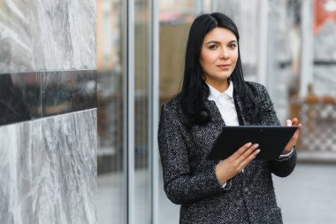 İş kadını binanın arka planında dijital tablet üzerinde çalışıyor