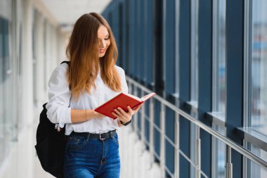 Pozitif, güzel bir kız kameraya gülümsüyor, koridorda sırt çantası gibi notlarla duruyor, derse gidiyor. Lüks üniversitede okuyan mutlu esmer kız öğrenci..