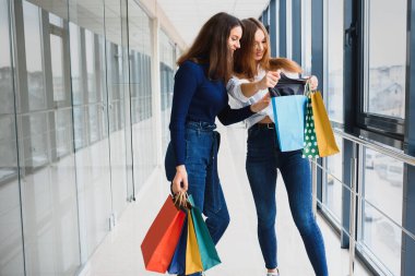 İki Kafkas kadının alışveriş merkezinde alışveriş yapmalarına sevindim. Alışveriş merkezinde iki genç kadın ellerinde poşetlerle yürüyor..