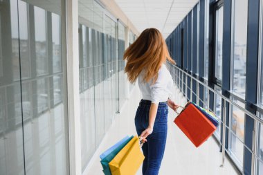 Alışveriş merkezinde çantaları olan güzel genç bir kadın.