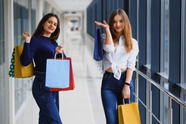 İki Kafkas kadının alışveriş merkezinde alışveriş yapmalarına sevindim. Alışveriş merkezinde iki genç kadın ellerinde poşetlerle yürüyor..
