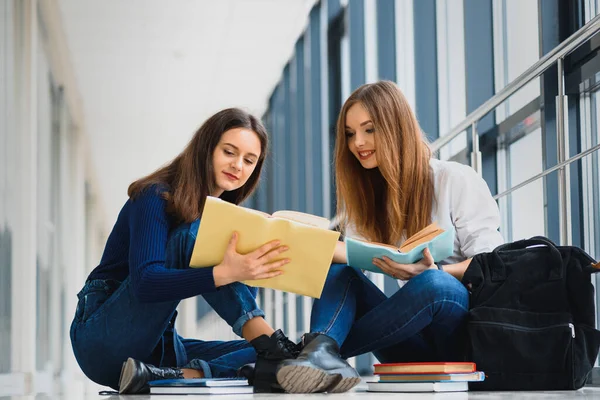 Две Симпатичные Студентки Книгами Сидящими Полу Университетском Коридоре — стоковое фото