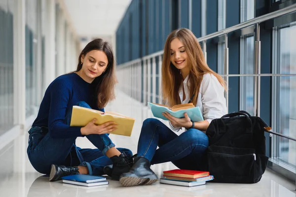 Две Симпатичные Студентки Книгами Сидящими Полу Университетском Коридоре — стоковое фото