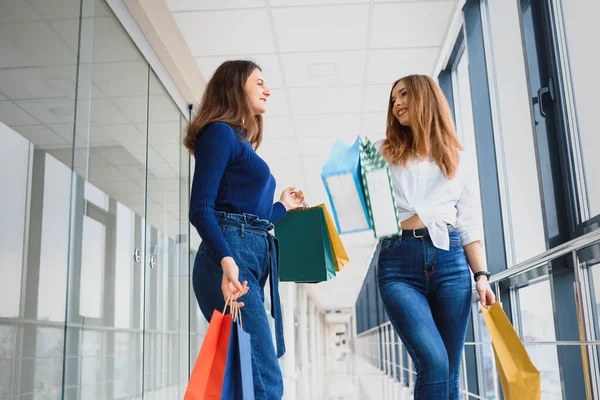 两个带着购物袋在购物中心散步的女朋友 — 图库照片