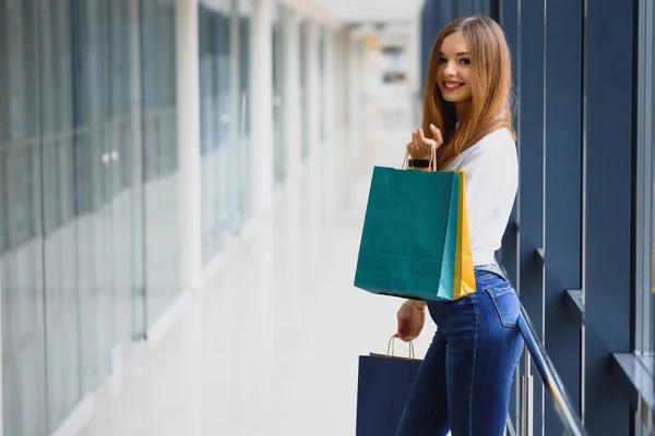Beautiful young woman with bags in shopping center