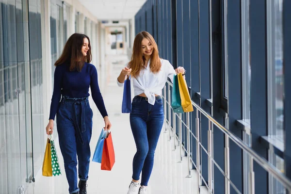 两个带着购物袋在购物中心散步的女朋友 — 图库照片
