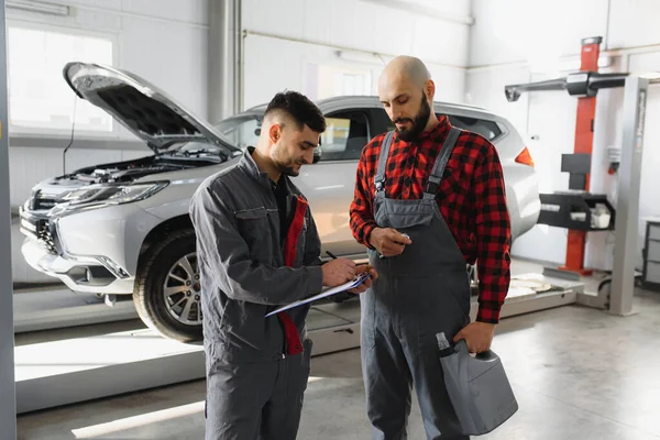Auto mechanics with tools near car in service center