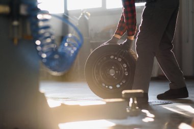 Garajda araba tekerleği tamir eden bir adam.